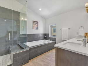 Bathroom with shower with separate bathtub, double vanity, and lofted ceiling