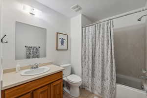 Full bathroom featuring vanity, toilet, tile patterned floors, and shower / bathtub combination with curtain