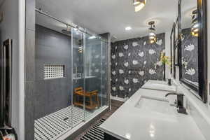 Bathroom featuring a shower with shower door, hardwood / wood-style flooring, and double vanity