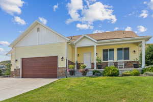 View of front of home featuring a porch, a garage, and a front yard