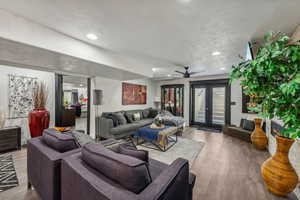 Living room featuring a textured ceiling, wood-type flooring, ceiling fan, and french doors