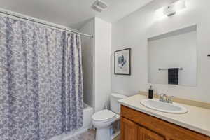 Full bathroom featuring vanity, shower / bathtub combination with curtain, toilet, a textured ceiling, and tile patterned flooring