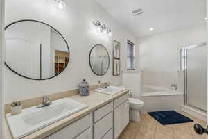 Full bathroom with plus walk in shower, tile patterned flooring, toilet, and dual bowl vanity