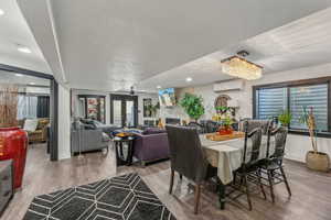 Dining room with a wall unit AC, a fireplace, french doors, and hardwood / wood-style flooring