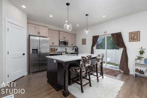 Kitchen featuring decorative light fixtures, stainless steel appliances, decorative backsplash, a center island with sink, and dark wood-type flooring