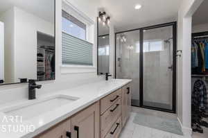 Bathroom with double vanity, tile patterned floors, and an enclosed shower