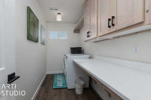 Laundry room featuring dark wood-type flooring, washing machine and dryer, and cabinets