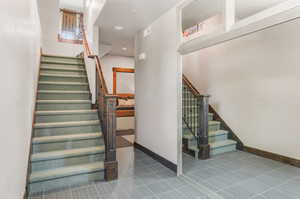 Stairway with a textured ceiling and tile patterned floors