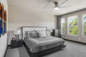 Carpeted bedroom featuring ceiling fan and a textured ceiling