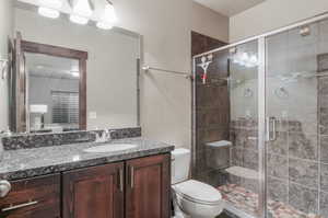 Bathroom featuring a shower with shower door, vanity, a textured ceiling, and toilet