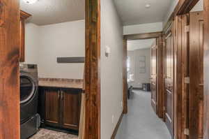 Interior space with cabinets, washer / clothes dryer, a textured ceiling, and light colored carpet