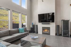 Living room featuring tile patterned flooring, a fireplace, and a towering ceiling