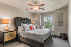 Carpeted bedroom with a textured ceiling and ceiling fan