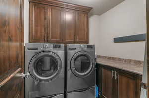 Washroom featuring washer and dryer, cabinets, and a textured ceiling