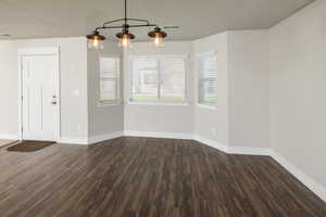 Empty room with dark hardwood / wood-style flooring and a healthy amount of sunlight