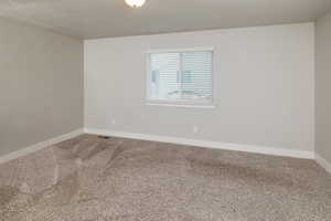 Carpeted empty room featuring a textured ceiling