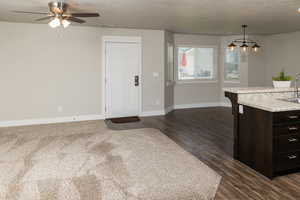 Kitchen featuring decorative light fixtures, dark brown cabinets, ceiling fan, sink, and dark carpet