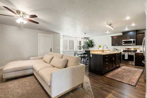 Living room with a textured ceiling, ceiling fan, sink, and dark hardwood / wood-style flooring