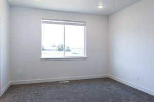 Unfurnished room featuring dark colored carpet