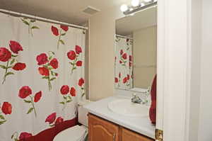 Bathroom with vanity, toilet, walk in shower, and a textured ceiling