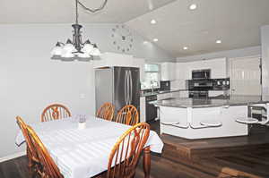 Dining space with high vaulted ceiling, dark hardwood / wood-style flooring, a notable chandelier, and sink