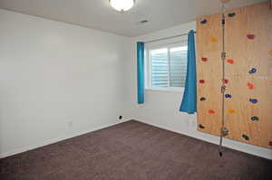 Spare room featuring dark colored carpet and a textured ceiling