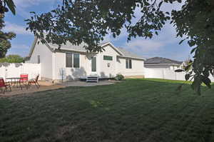 Back of house with a lawn and a patio