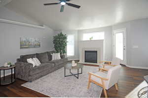 Living room featuring ceiling fan, vaulted ceiling, dark hardwood / wood-style flooring, and a fireplace