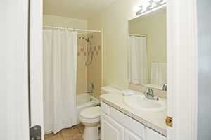 Full bathroom featuring vanity, toilet, shower / tub combo, and tile patterned floors