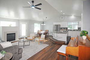 Living room featuring ceiling fan with notable chandelier, dark wood-type flooring, plenty of natural light, and a tile fireplace