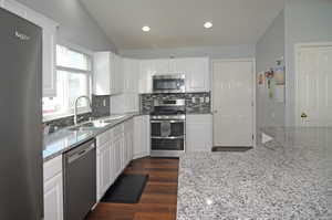 Kitchen featuring dark hardwood / wood-style flooring, light stone counters, stainless steel appliances, and sink