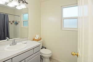 Bathroom with toilet, a wealth of natural light, and vanity