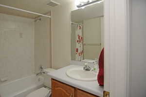 Full bathroom featuring vanity, toilet, a textured ceiling, and shower / bath combo with shower curtain