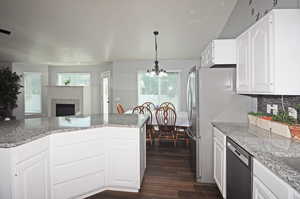 Kitchen featuring a fireplace, appliances with stainless steel finishes, plenty of natural light, and an inviting chandelier