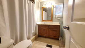 Full bathroom featuring vanity, toilet, tile floors