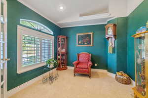 Sitting room with carpet flooring, crown molding, and vaulted ceiling