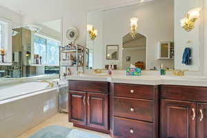 Bathroom with vanity, tile patterned flooring, and a relaxing tiled tub