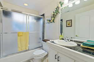 Full bathroom with vanity, tile patterned floors, combined bath / shower with glass door, and toilet