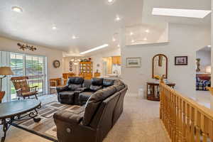 Carpeted living room with a skylight, sink, an inviting chandelier, and high vaulted ceiling