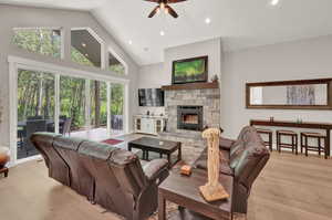 Living room featuring ceiling fan, a fireplace, light hardwood / wood-style floors, and plenty of natural light