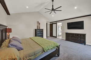 Bedroom with connected bathroom, a barn door, carpet floors, and ceiling fan