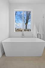 Primary Bathroom featuring tile floors, plenty of natural light, a mountain view, and a tub to relax in