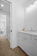 Connecting bathroom featuring tile flooring, vanity, and a tub to relax in