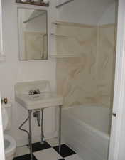 Bathroom with shower / washtub combination, tile patterned floors, and toilet