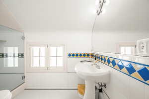 Bathroom featuring a wealth of natural light, tile patterned flooring, toilet, and tile walls