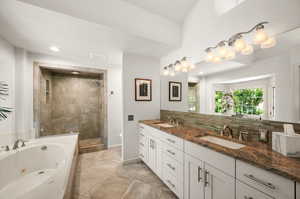 Primary Bathroom featuring double vanity, plus walk-in shower, tasteful backsplash, and tile patterned floors