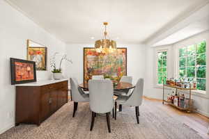 Dining area featuring a chandelier, light wood flooring, and ornamental molding