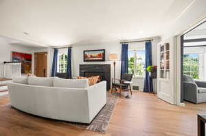 Living room with light hardwood / wood floors, crown molding, and a premium fireplace