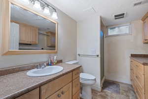 Bathroom with tile patterned floors, toilet, vanity, and a textured ceiling