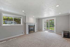 Unfurnished living room with a premium fireplace, carpet, a wealth of natural light, and crown molding